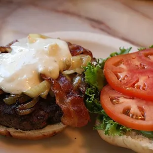 a burger with bacon, tomatoes, lettuce, and onions