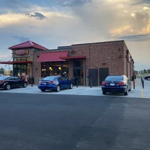 the outside of a restaurant with cars parked in front of it