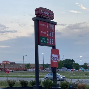 a gas station sign and a car in the parking lot