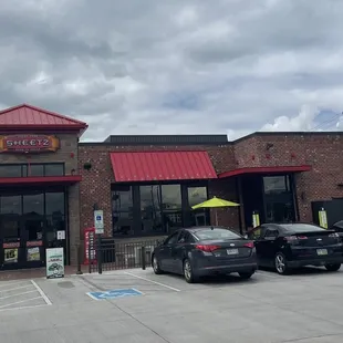 the outside of a restaurant with cars parked in front of it