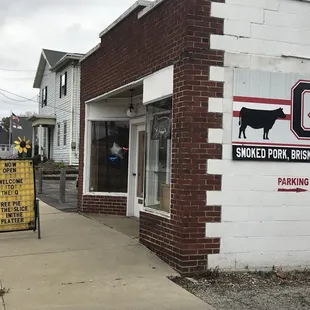 a brick building with a sign on the sidewalk