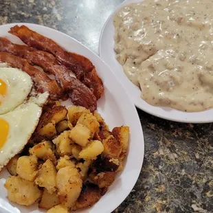 Biscuits and gravy with eggs, bacon, and home fries.