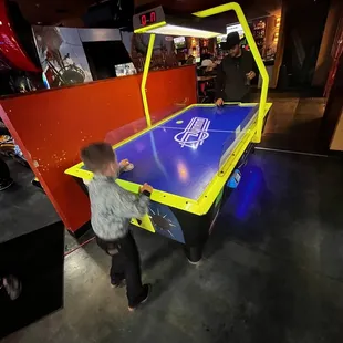 a young boy playing a game of air hockey