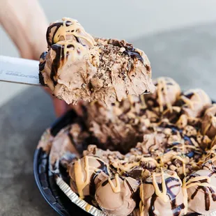 a person scooping a scoop of ice cream into a pie