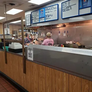 a woman in a pink shirt behind the counter