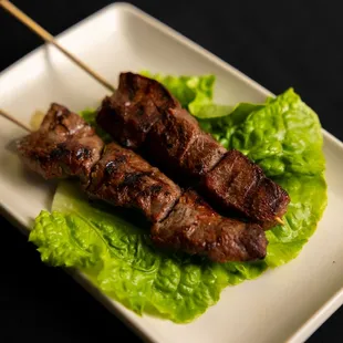 two skewers of meat on a bed of lettuce