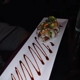 a long rectangular plate of food with sauce drizzled over it