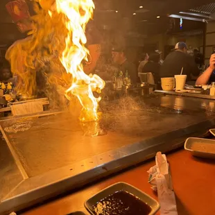 a man cooking on a grill with flames coming out of it