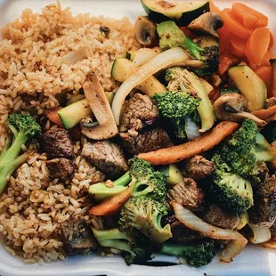 a white styrofoam container filled with rice and vegetables