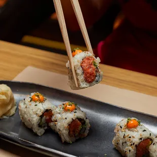 a person holding chopsticks above a plate of sushi