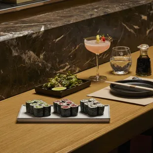 a table with sushi and a glass of wine