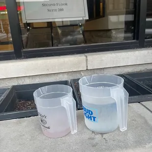 two cups of water on the sidewalk