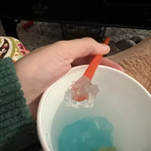 a person holding a bowl of liquid and a carrot
