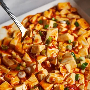 tofu in a dish with sauce and green onions