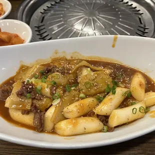 Tteokbokki: long rice, cake, and stirfried beef in spicy pepper paste sauce, fishcakes, scallions, onions with beef broth