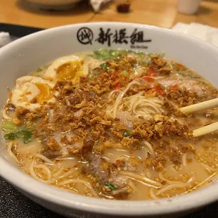 ows a bowl of ramen with chopsticks