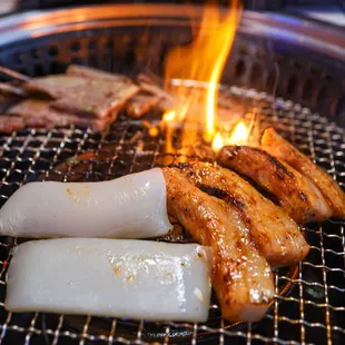 a variety of meats being cooked on a grill