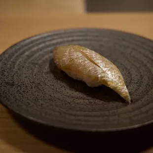 a piece of sushi on a black plate