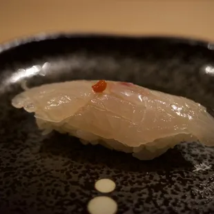 a close up of a piece of sushi on a black plate