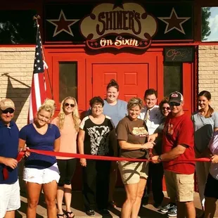 a group of people cutting a ribbon