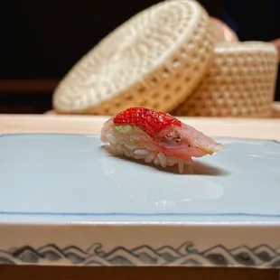 a sushi on a plate with a straw hat in the background