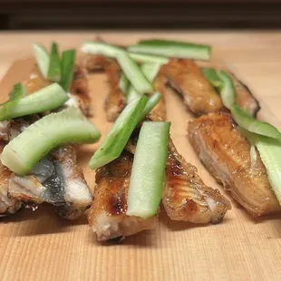 a wooden cutting board topped with sliced fish and cucumbers