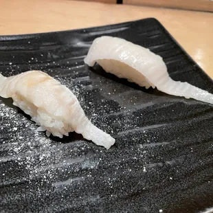 two pieces of sushi on a black plate