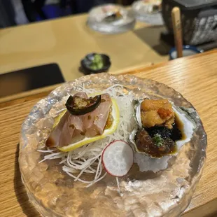 Oyster topped with caviar Uni and a refreshing sauce next to yellowtail jalapeño style sashimi.