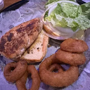 Grilled chicken with onion and lettuce with side of onion rings.