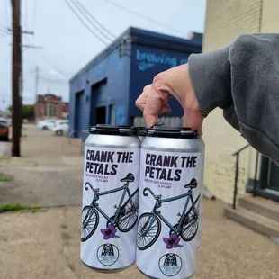 Crank the Petals Hibiscus Hazy Pale Ale Canned 4 Pack. Shipping Port in the background