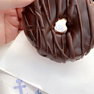 a hand holding a chocolate donut