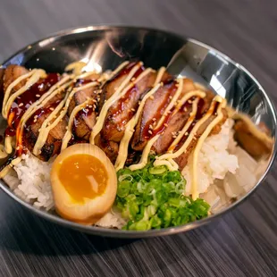 a bowl of food with rice, egg, and sauce