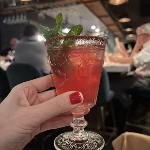a person holding a glass of cocktail