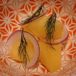 two slices of sliced radishes on an orange and white plate