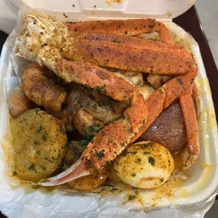 crab legs and potatoes in a styrofoam container