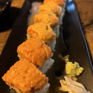 a black rectangular plate with a sushi roll on it