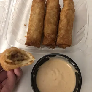 a hand holding a piece of food and dipping sauce