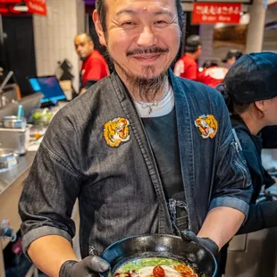 a man holding a bowl of ramen