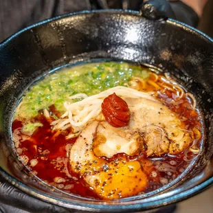 a person holding a bowl of ramen