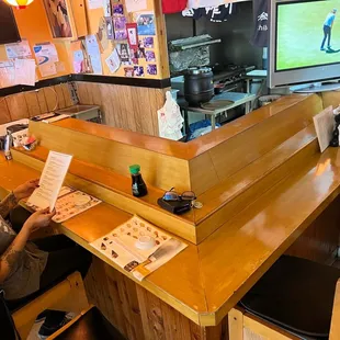 a woman sitting at the bar reading a menu