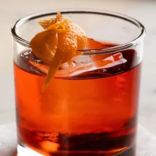 a drink in a glass with an orange garnish