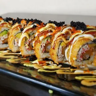 a long roll of sushi on a black plate