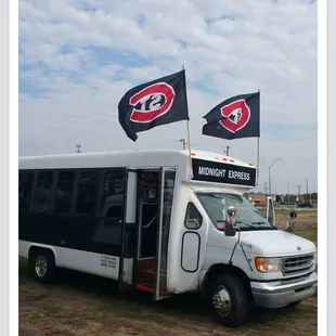 a white bus with two flags on top