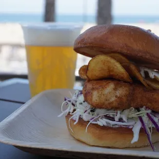 a fish sandwich with coleslaw slaw and a beer