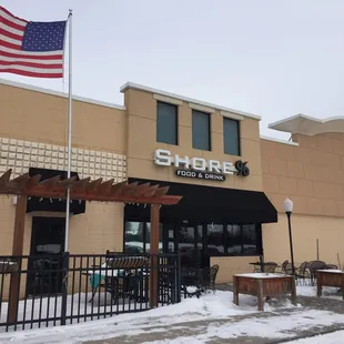 the front of a restaurant with an american flag flying in the wind