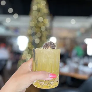a hand holding a glass with a drink in it
