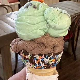 a hand holding an ice cream cone with sprinkles