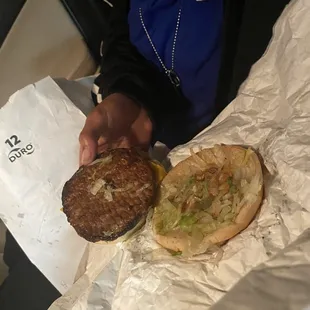 a person holding a hamburger and a sandwich