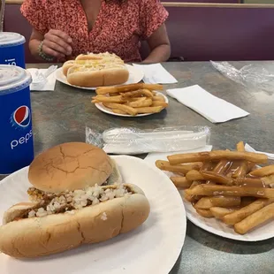 a woman sitting at a table with a sandwich and fries