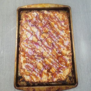 a square pizza with onions and caramel